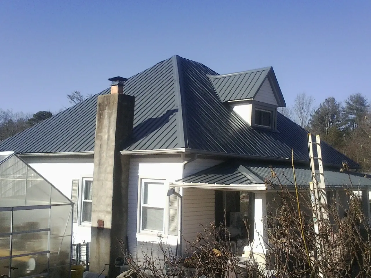 Dark blue standing seam metal roof on a white farmhouse with dormer — Slate & Tile Roof Repair by Roofing Brothers in Granada Hills