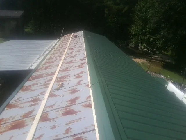 Old rusted panels beside newly installed green metal roofing — Wind Damage Roof Repair by Roofing Brothers in Granada Hills