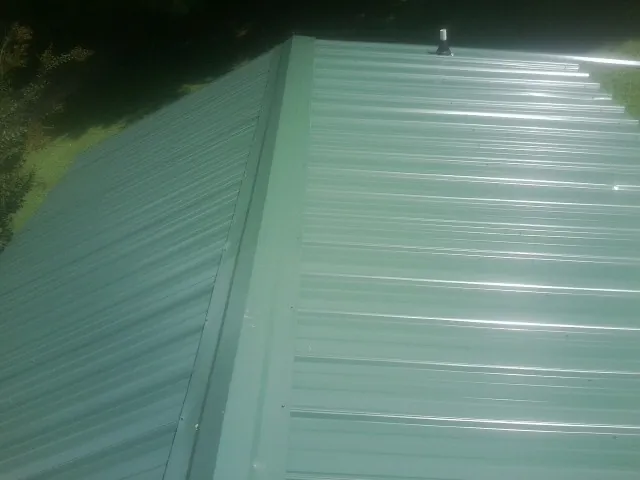 New green metal panels meeting at the ridge of a roof — Flat Roof Repair work by our crew in Granada Hills