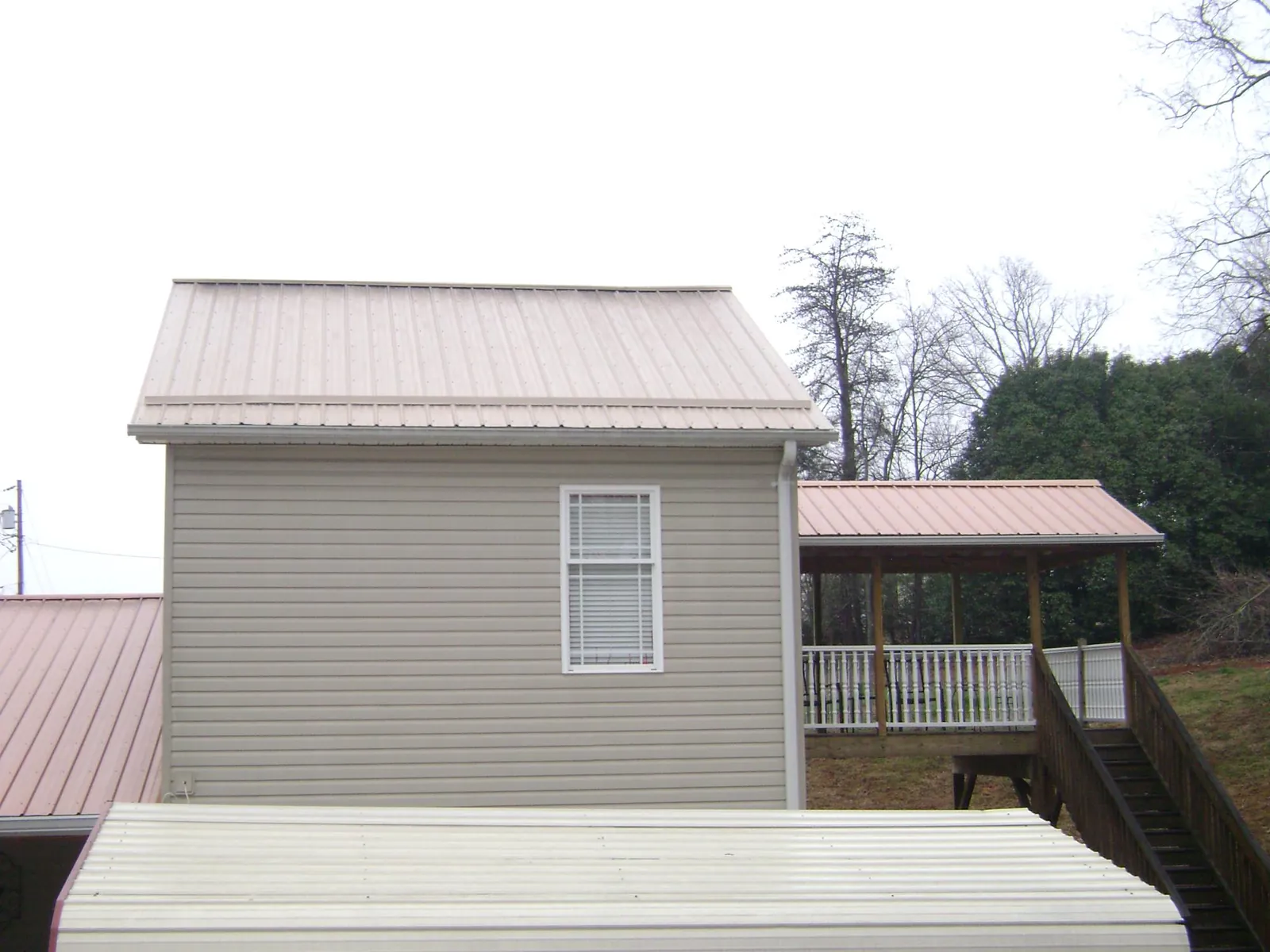 Tan metal roofs on a two story addition and attached porch, from a Roof Replacement job in Granada Hills