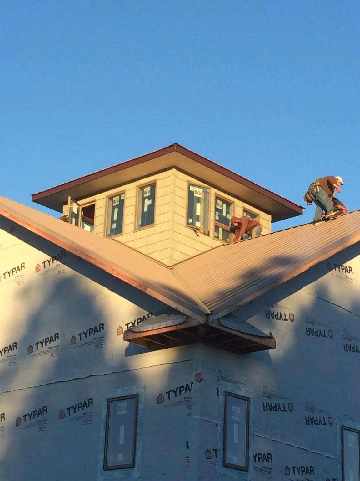 Roofers working around a rooftop cupola on a new metal roof at sunset — Roof Waterproofing in Granada Hills by Roofing Brothers